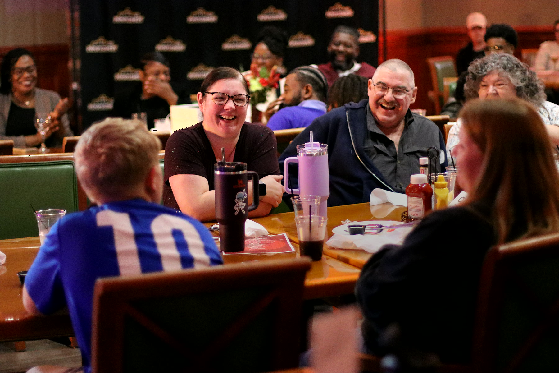 A packed table of guests laughing at a Popups Comedy night