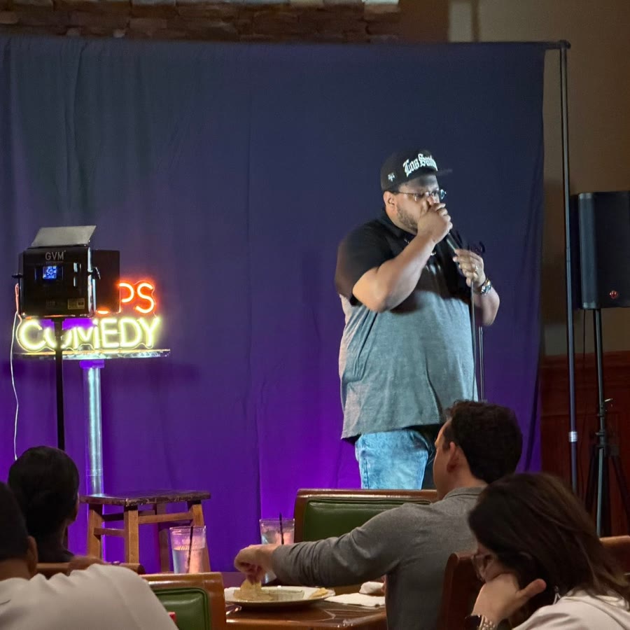 A comic on stage with a full front table watching