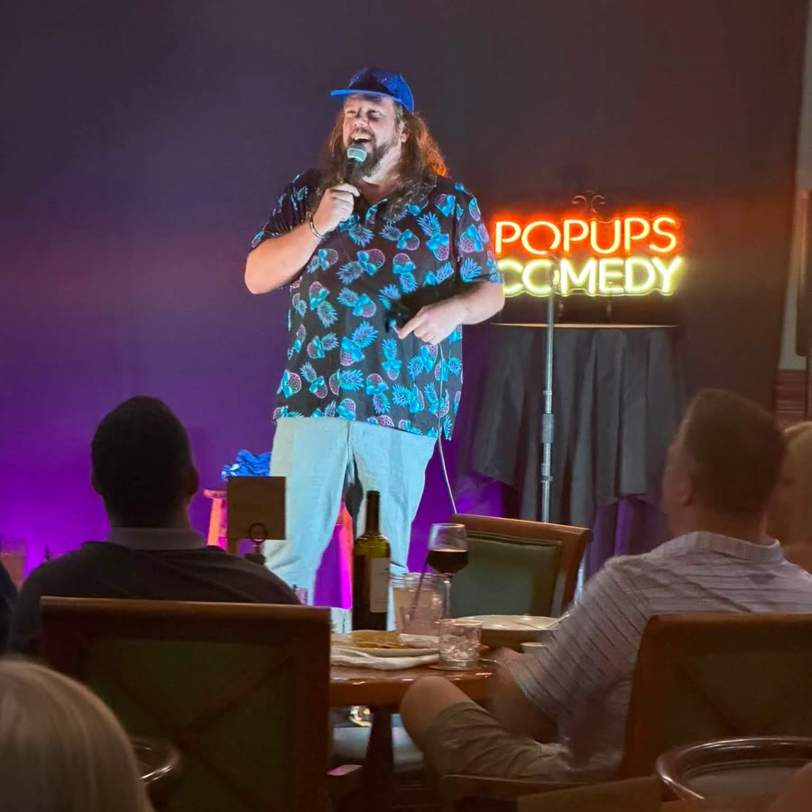 A comic on stage with the tables full