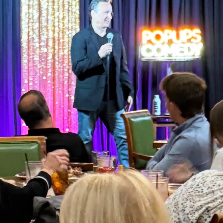 A comic on stage in front of a full house